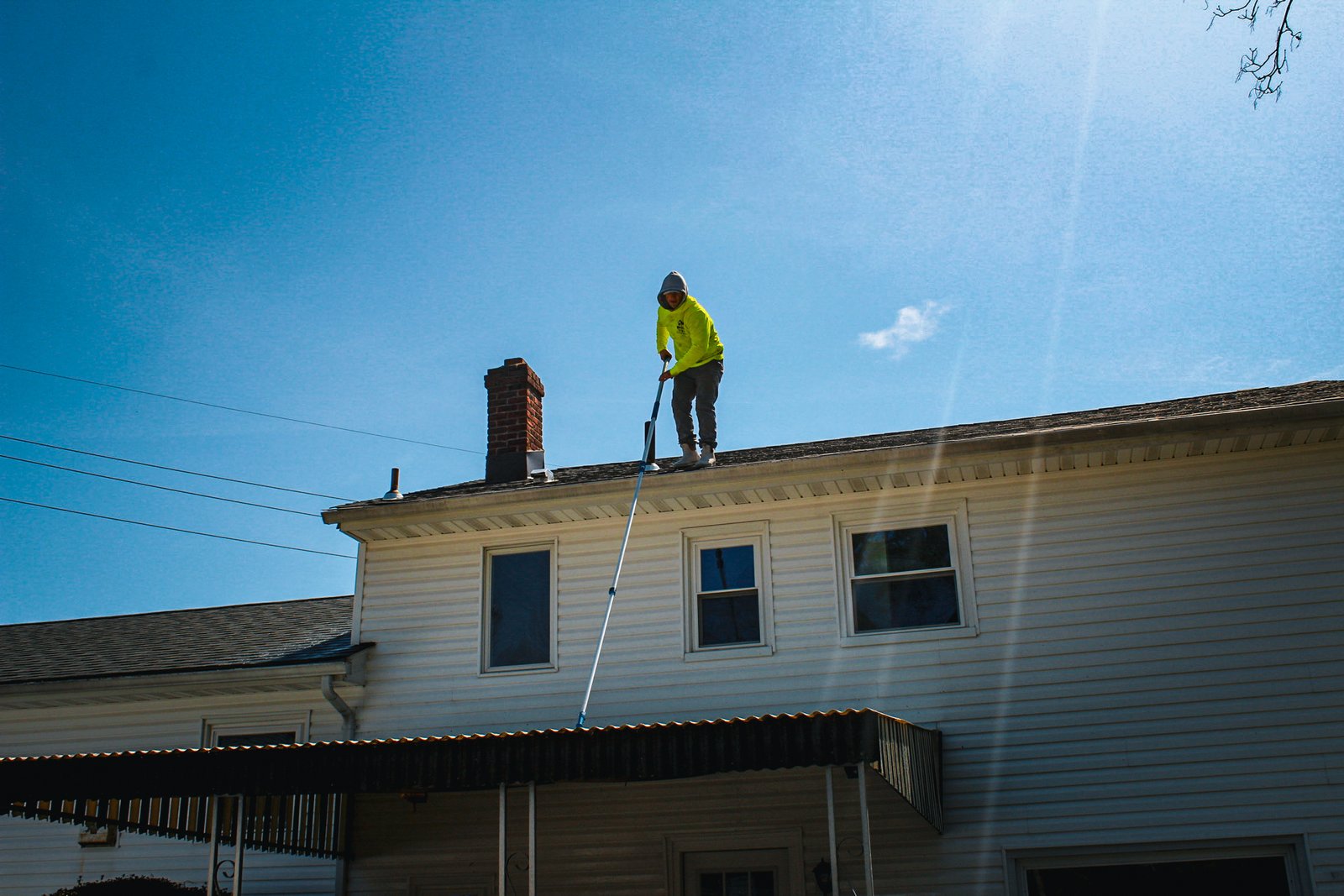 Darius cleaning a home exterior from the roof in North Jersey